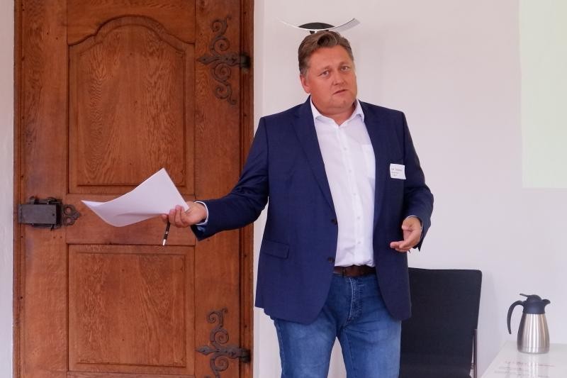 Mann mit Blatt in der Hand vor einer Holztür